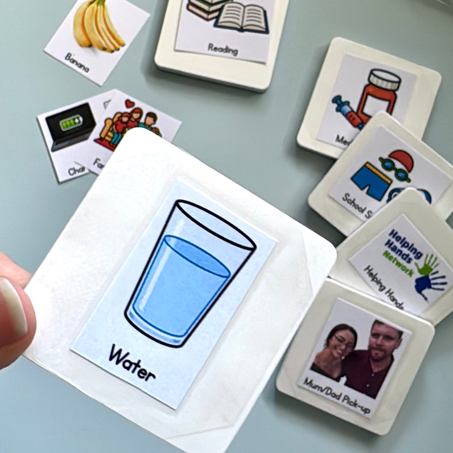 a selection of blank magnets with stickers in the background and a close up of a magnet with the sticker with the words water and a glass of water on the surface of the magnet