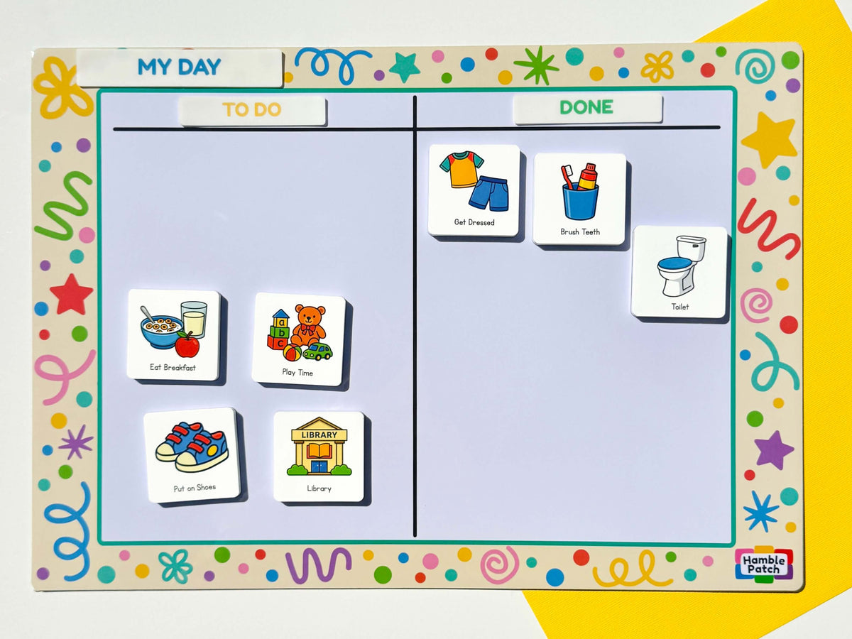 A children's daily planning magnetic board with colourful decorative border, a 'MY DAY' header, and columns labelled 'TO DO' and 'DONE'. Magnetic activity tiles showing breakfast, play time, shoes, library, clothes, brush teeth, and toilet are arranged on the board.