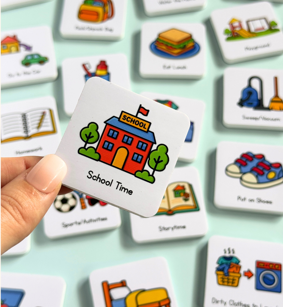 Hand holding a magnet with a school-themed illustration among other child friendly magnets on a light green background.