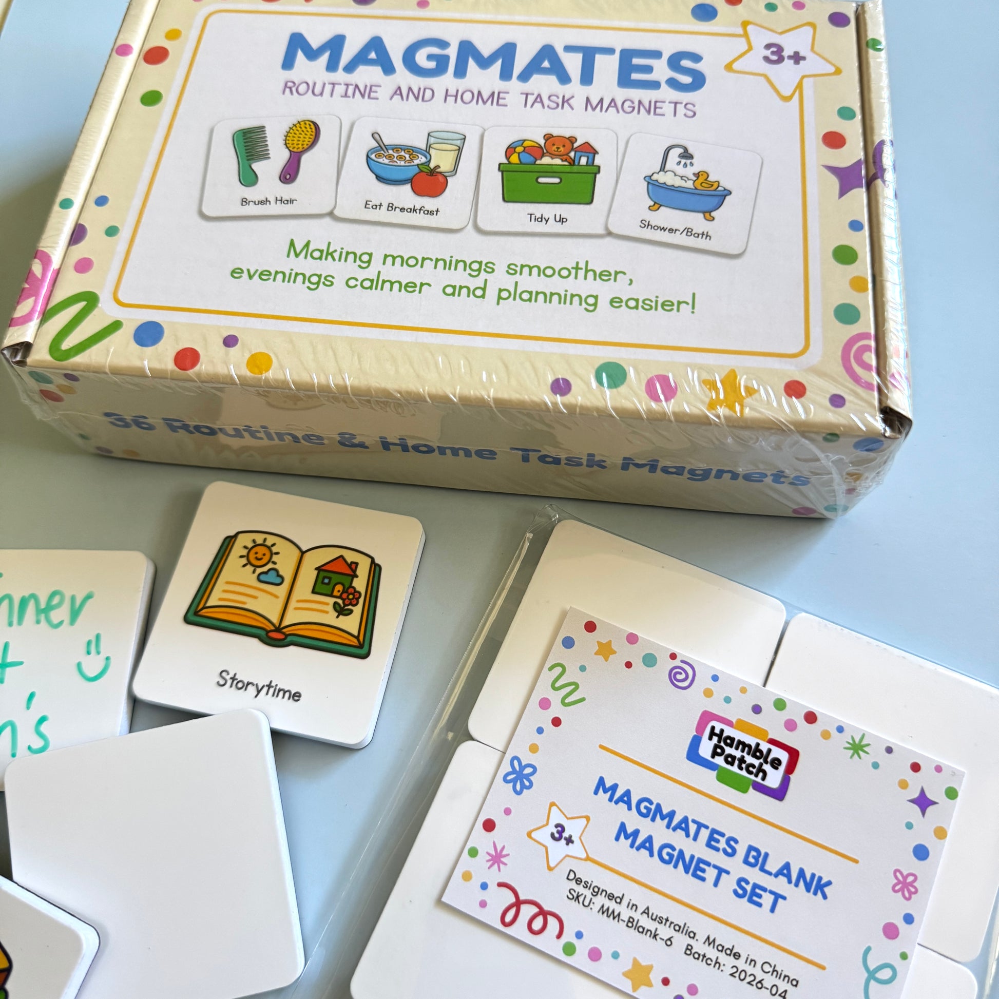 A box of MagMates Routine and Home Task Magnets and a set of MagMates Blank Magnets on a blue background with a couple of the magnets positioned beside them.