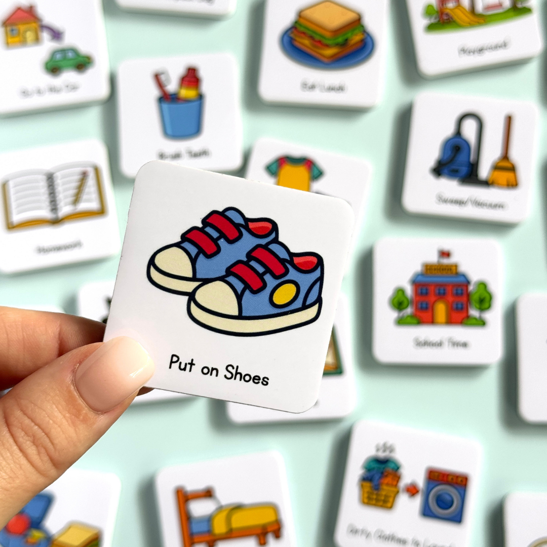 Magnet with shoes illustration and 'Put on Shoes' text held by a hand, surrounded by other routine magnets.
