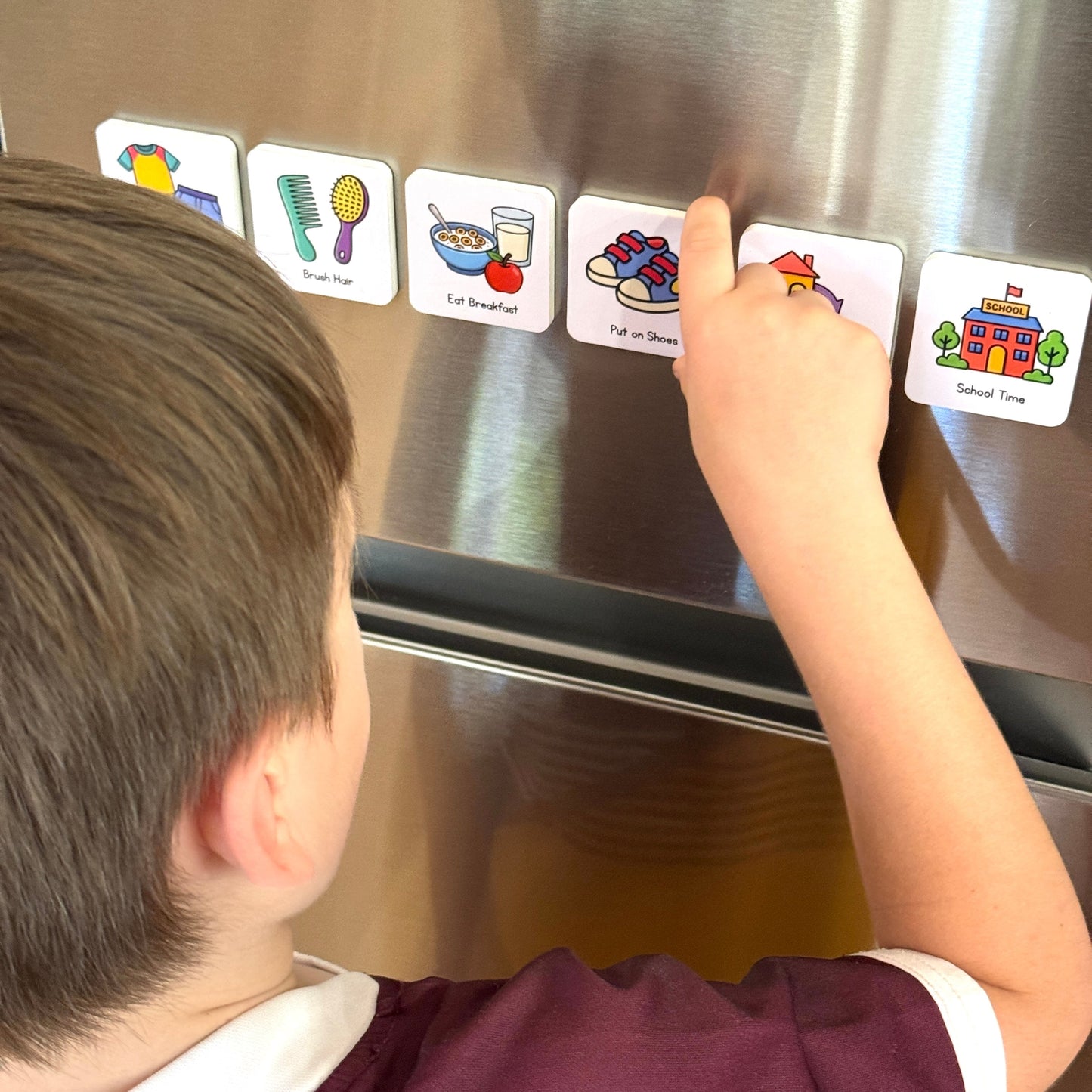 Child interacting with routine magnets on a refrigerator door