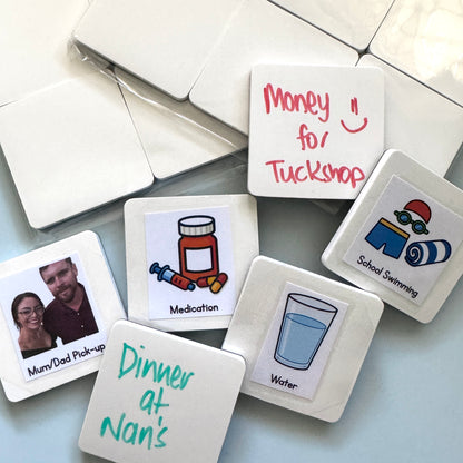 A selection of blank white magnets with a selection of either stickers or words written in dry-erase on the surface of them, such as money for tuckshop, school swimming and water. 