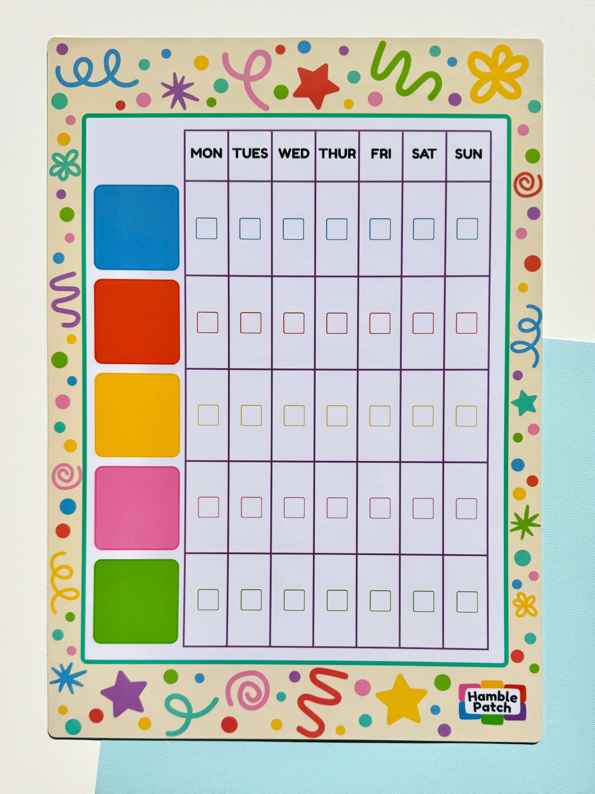 A colourful weekly planner board by Hamble Patch, featuring a grid from Monday to Sunday with check boxes, five coloured day markers on the left, and a playful multicolour border.