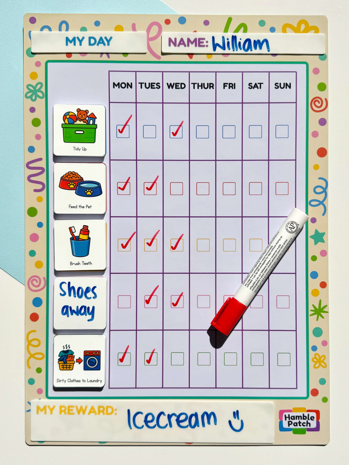 A children's daily routine chart with a grid for Monday through Sunday, labeled 'MY DAY' at the top. The chart includes small illustrated task magnets on the left, a red-and-white marker placed diagonally across the right side, and a handwritten reward note at the bottom.